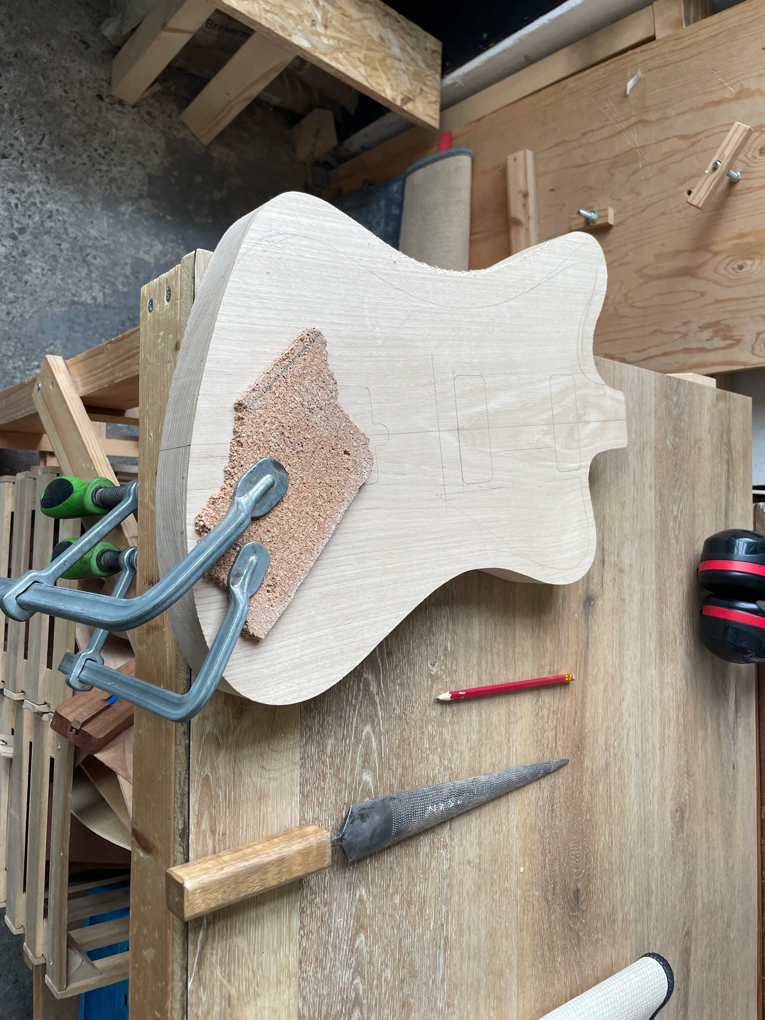 Here the guitar body is clamped onto the edge of my bench. I’ll use a rasp to carve a contour onto the edge.