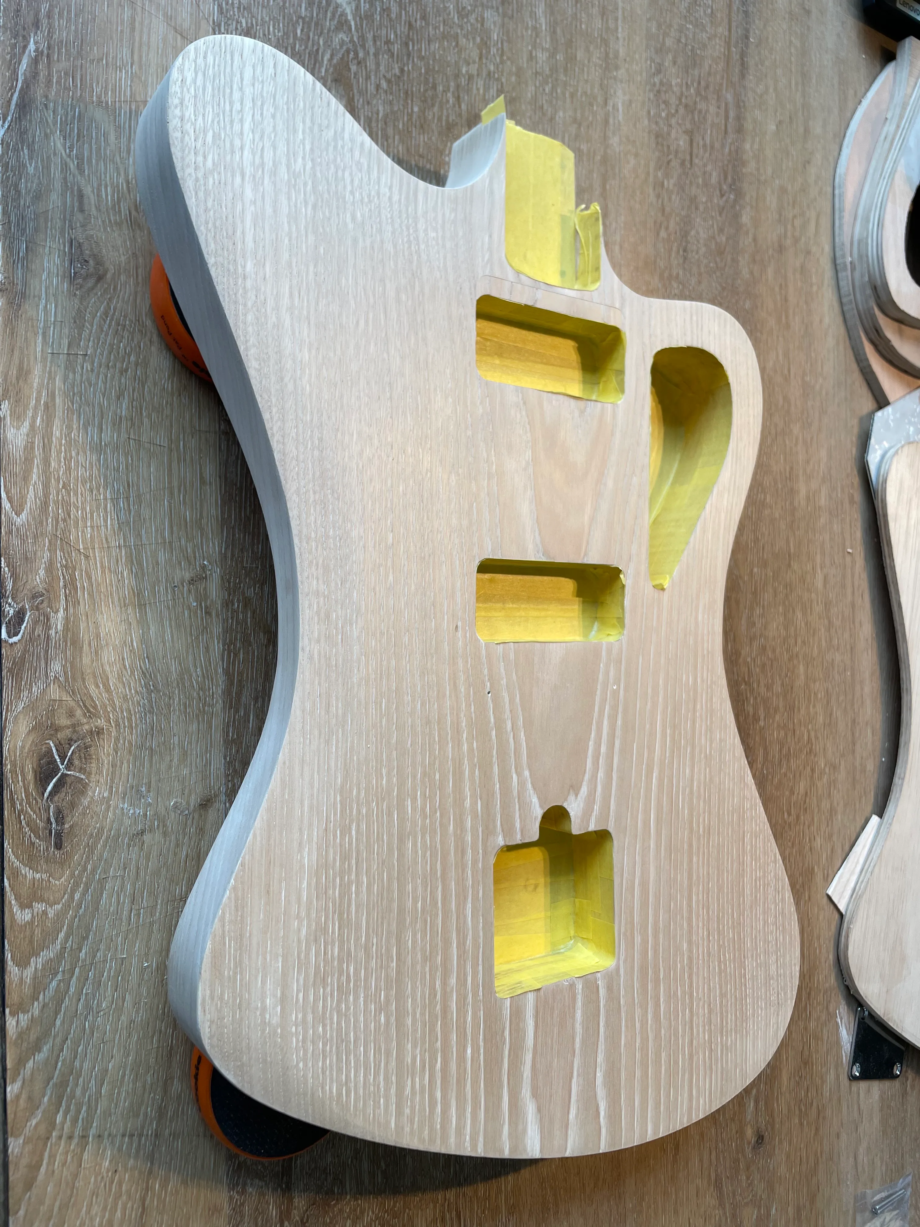 The cavities are all filled with yellow tape. Next step is to cover the body in a layer of blue dye, before lacquering. The grain should show through nicely