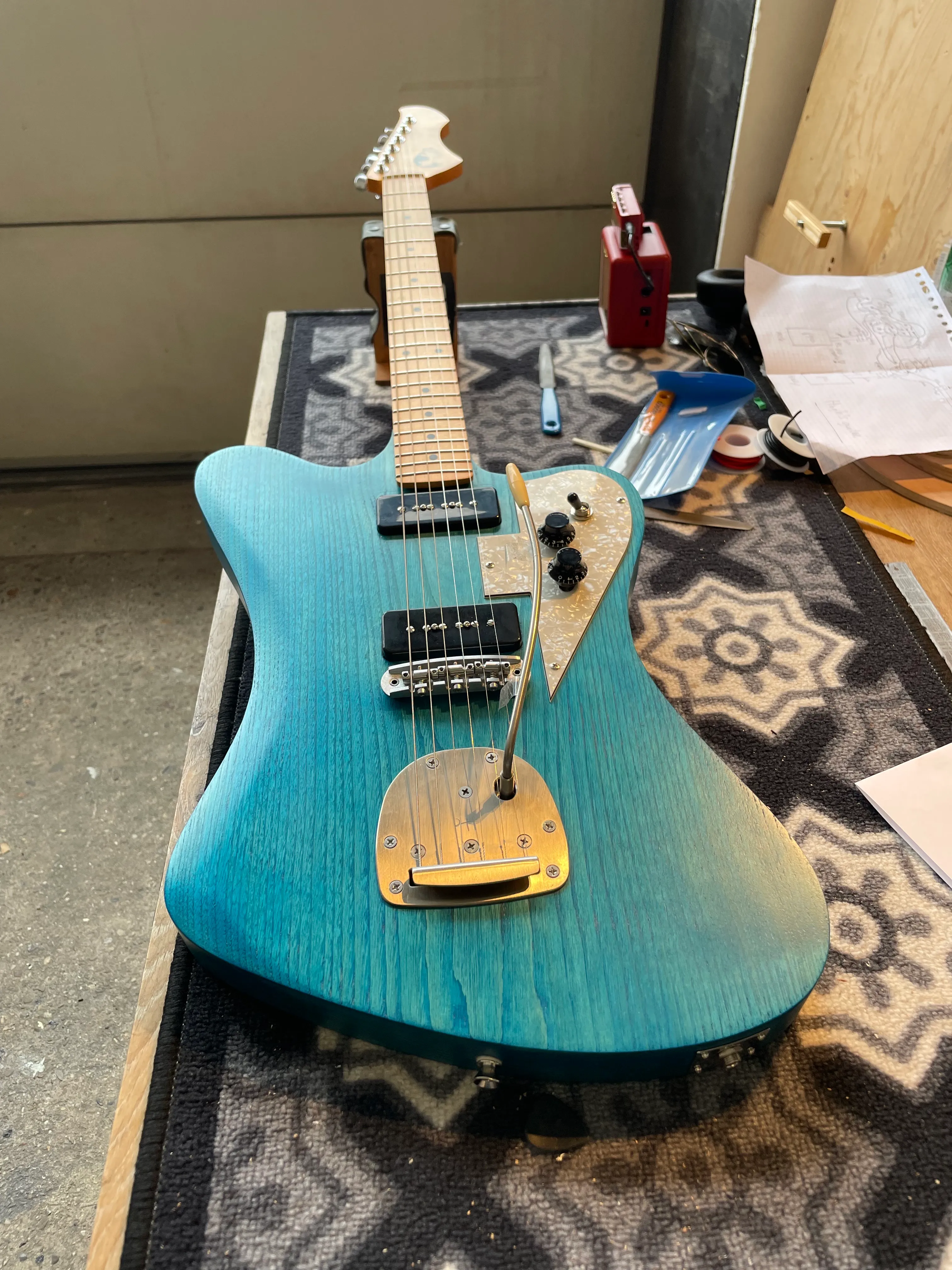 Yesterday was a wild day, involving hotel checkout, various transport methods, a hectic day in the workshop, several near-disasters, and all on top of the exhaustion of having spent the last 2 weeks like this. But it is done. It’s indisputably a working guitar. I have yet to play it very much, because playing at the workshop was deemed gauche somehow, and I visited friends last night and didn’t want to just be off playing guitar in a corner on my own. I’ll write something up about some of the problems, mistakes, things that look like mistakes but are actually design decisions, and happy accidents (mainly that blue), but for now, I’ll have a cup of coffee and spend my morning playing my guitar!